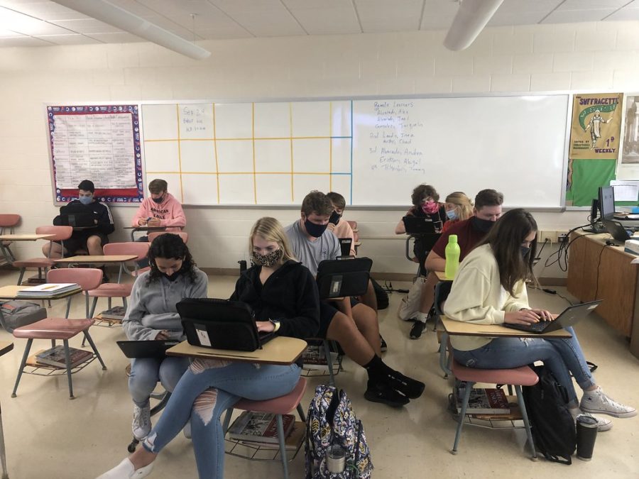 A group of students work in a classroom with their faces covered. While this was common in 2020, it is no longer a school requirement.