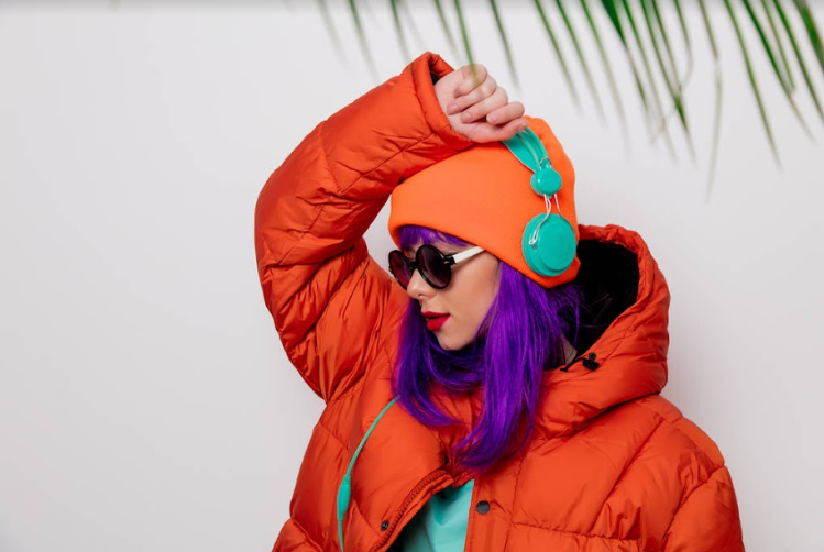 A girl listens to music in a bright orange coat on the beach.
Photo Credit:TarasMalyarevich